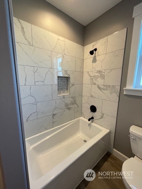 bathroom featuring tiled shower / bath combo and toilet