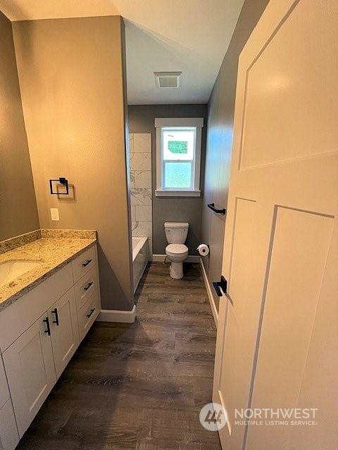 bathroom with toilet, hardwood / wood-style floors, and vanity