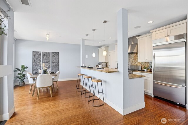 1501 Tacoma Ave S Unit 603, Tacoma, WA 98402 - kitchen featuring built in refrigerator, wood finished floors, tasteful backsplash, a kitchen bar, and white cabinets