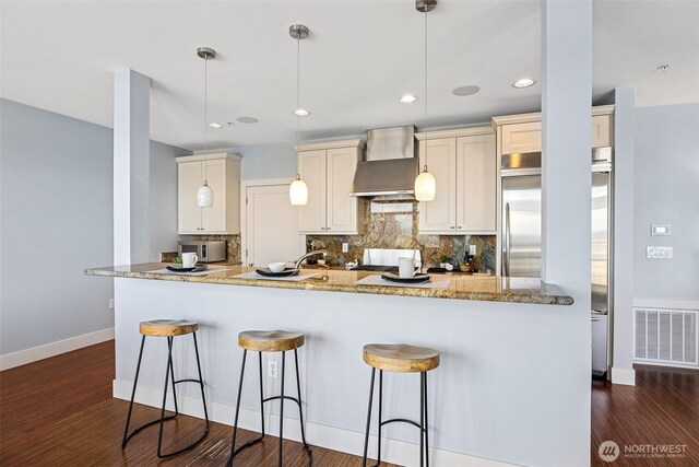 1501 Tacoma Ave S Unit 603, Tacoma, WA 98402 - kitchen featuring wall chimney range hood, decorative backsplash, baseboards, a kitchen bar, and recessed lighting
