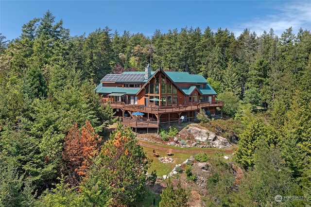 back of property with solar panels and a deck