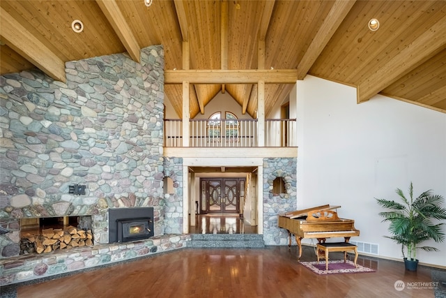 interior space featuring high vaulted ceiling, beam ceiling, hardwood / wood-style floors, and a stone fireplace