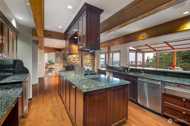 kitchen with appliances with stainless steel finishes, light hardwood / wood-style floors, dark stone counters, beam ceiling, and tasteful backsplash