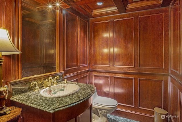 bathroom with coffered ceiling, toilet, wood walls, and vanity