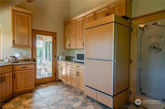 kitchen featuring light tile flooring, light stone countertops, and white appliances