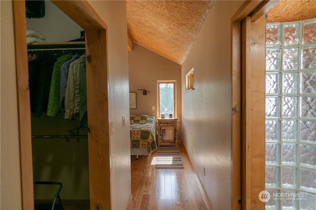 hall with lofted ceiling and light wood-type flooring