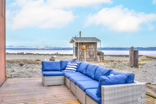 deck with a water view, outdoor lounge area, and an outdoor structure