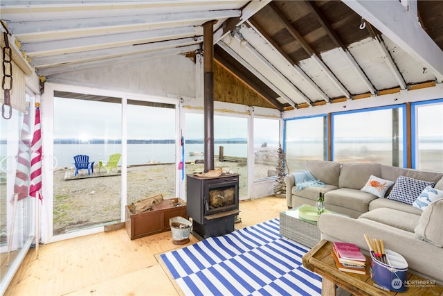 sunroom / solarium featuring lofted ceiling, a water view, and a wood stove