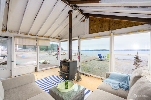 sunroom / solarium featuring a water view, a wood stove, and vaulted ceiling with beams