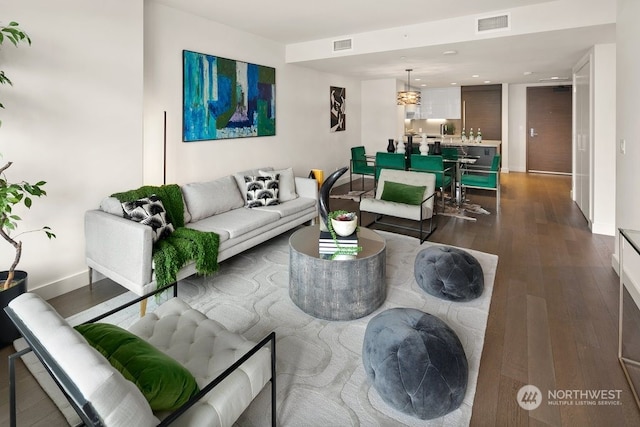 living room featuring a chandelier and dark wood-type flooring