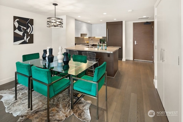 dining room with sink, an inviting chandelier, and dark hardwood / wood-style flooring