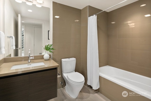 full bathroom featuring tile walls, toilet, vanity, and shower / tub combo