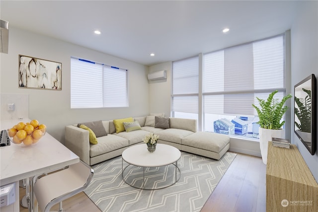 living room with a wall mounted AC and light hardwood / wood-style flooring