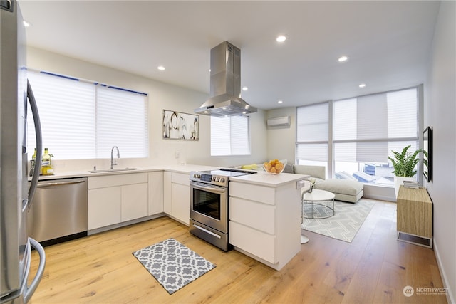 kitchen featuring stainless steel appliances, light hardwood / wood-style floors, sink, white cabinetry, and island range hood