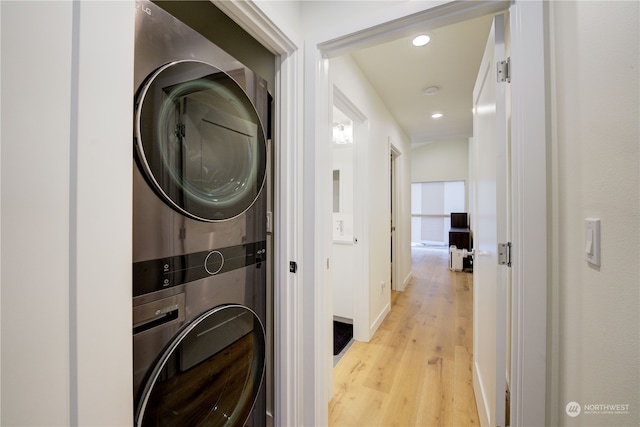 washroom with stacked washer / drying machine and light hardwood / wood-style floors