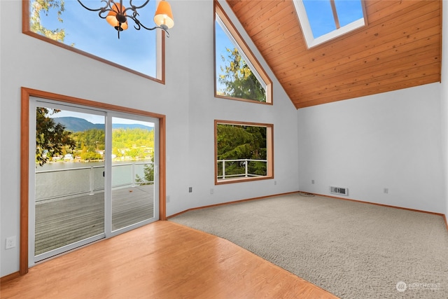 carpeted empty room with a chandelier, a skylight, wooden ceiling, and high vaulted ceiling