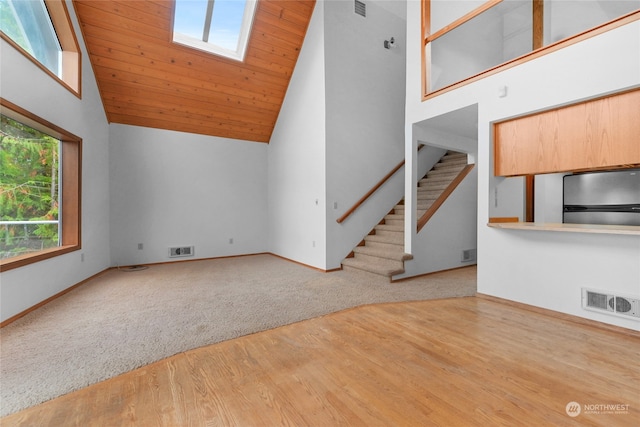 unfurnished living room featuring high vaulted ceiling, light hardwood / wood-style flooring, and a skylight