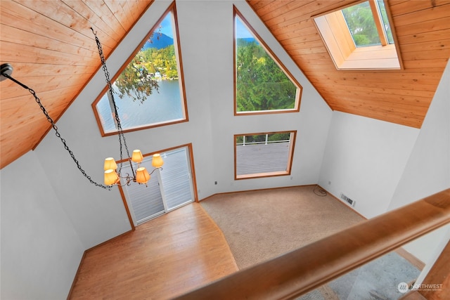 entrance foyer featuring lofted ceiling with skylight, wood ceiling, light carpet, and an inviting chandelier