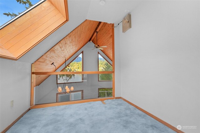 interior space featuring carpet, ceiling fan with notable chandelier, and vaulted ceiling