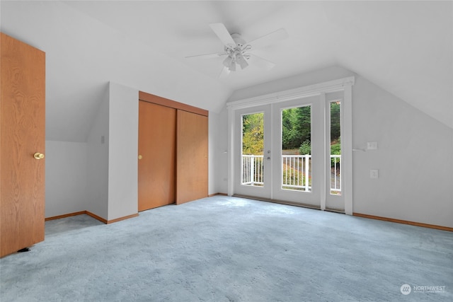 unfurnished bedroom with light carpet, a closet, access to exterior, ceiling fan, and lofted ceiling