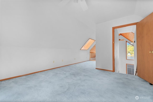 carpeted empty room with lofted ceiling with skylight and ceiling fan