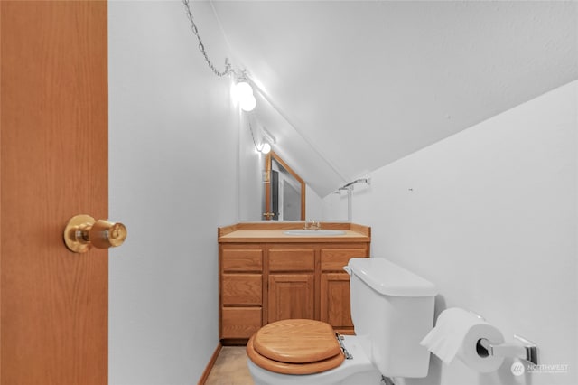 bathroom with tile flooring, vanity, toilet, and vaulted ceiling