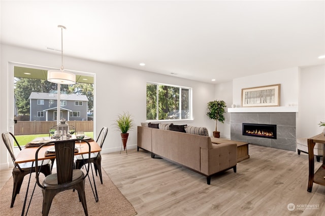 living room with light wood-type flooring and a tiled fireplace