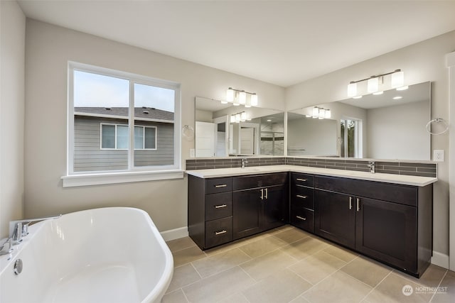 bathroom with dual vanity, tile patterned floors, a bathing tub, and backsplash