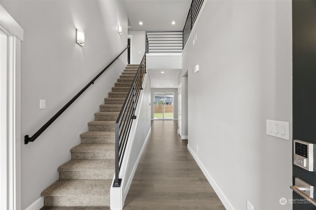 stairway with a high ceiling and hardwood / wood-style flooring