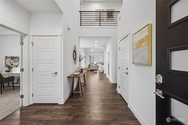 foyer entrance with dark wood-type flooring and a towering ceiling