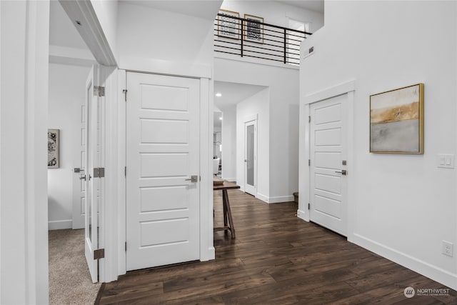 hall featuring a towering ceiling and dark hardwood / wood-style flooring