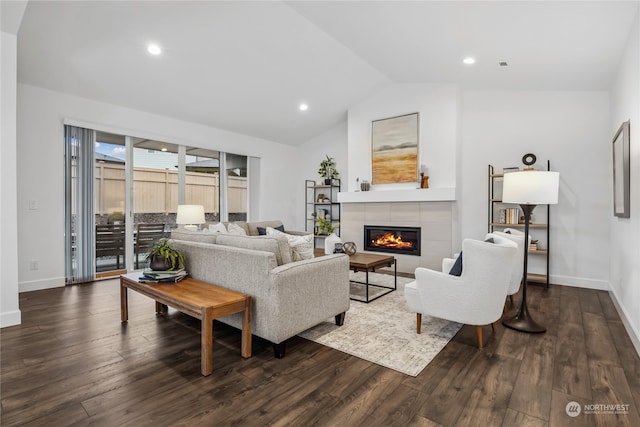 living room featuring a tiled fireplace, vaulted ceiling, and dark hardwood / wood-style floors