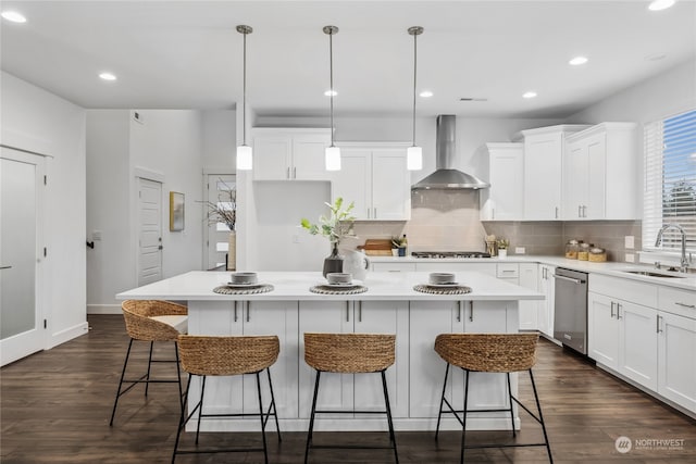 kitchen with sink, stainless steel appliances, a center island, and wall chimney exhaust hood