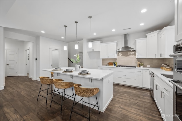 kitchen featuring white cabinetry, wall chimney range hood, and a center island