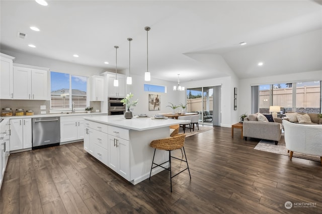 kitchen with white cabinetry, decorative light fixtures, a center island, and appliances with stainless steel finishes