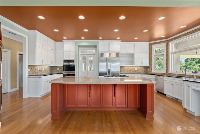 kitchen featuring light wood-type flooring, appliances with stainless steel finishes, a center island, and light stone countertops