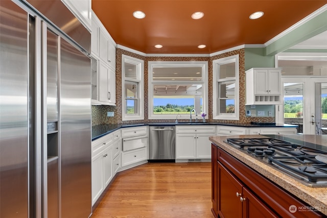 kitchen featuring appliances with stainless steel finishes, light hardwood / wood-style floors, crown molding, backsplash, and sink