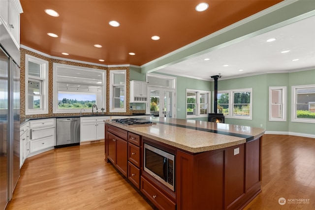 kitchen with white cabinets, light hardwood / wood-style flooring, and built in appliances