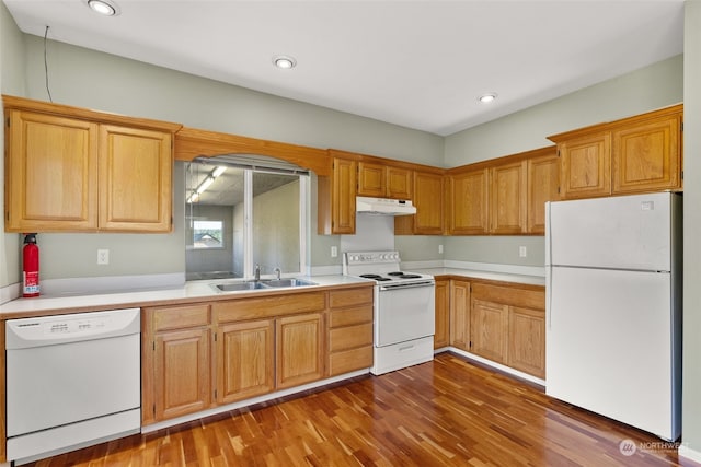 kitchen with white appliances, sink, and wood-type flooring