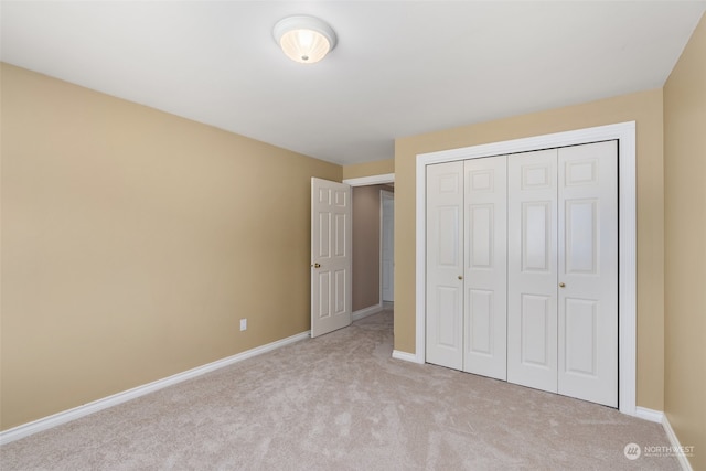 unfurnished bedroom with a closet and light colored carpet