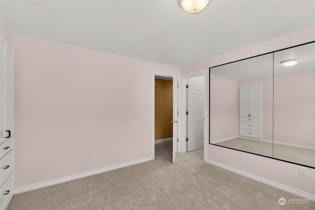 unfurnished bedroom with a closet and light colored carpet