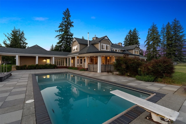 view of pool with a patio and a diving board