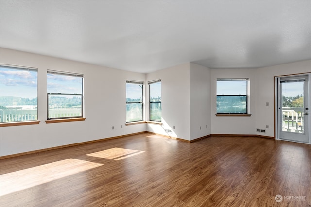 empty room with plenty of natural light and dark wood-type flooring