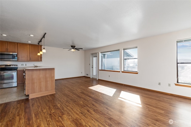 kitchen featuring dark tile floors, decorative light fixtures, stainless steel appliances, and plenty of natural light