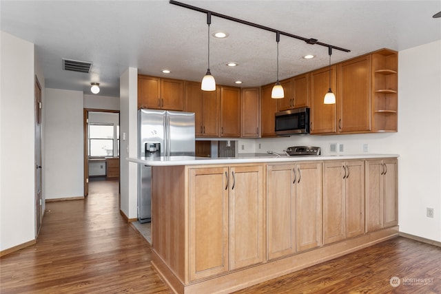 kitchen featuring hanging light fixtures, stainless steel appliances, kitchen peninsula, and wood-type flooring