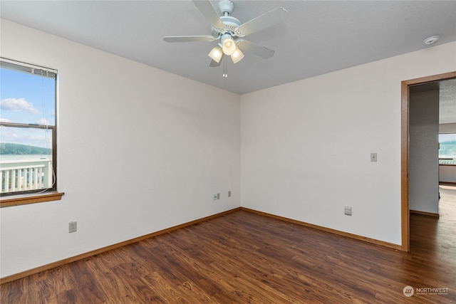 spare room featuring dark hardwood / wood-style floors, ceiling fan, and plenty of natural light