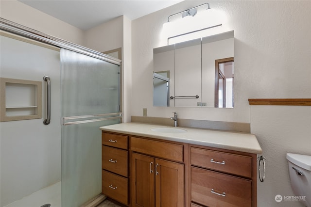 bathroom with toilet, large vanity, and a shower with door