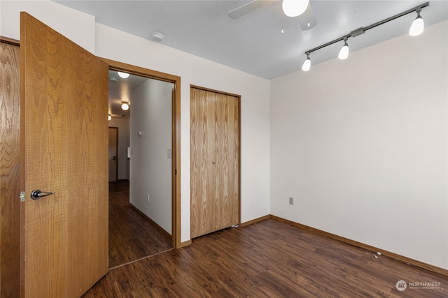 unfurnished bedroom featuring dark hardwood / wood-style flooring, ceiling fan, and rail lighting