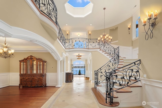 entryway featuring hardwood / wood-style floors, a chandelier, a wealth of natural light, a high ceiling, and ornamental molding