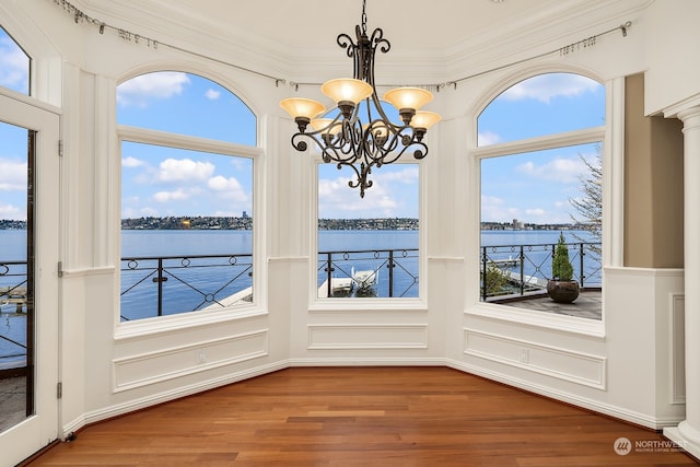 unfurnished dining area featuring ornamental molding, hardwood / wood-style flooring, and a water view